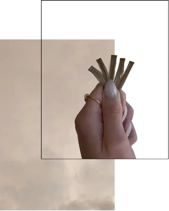 Hand holding fan of dollar bills against cloudy sky background.