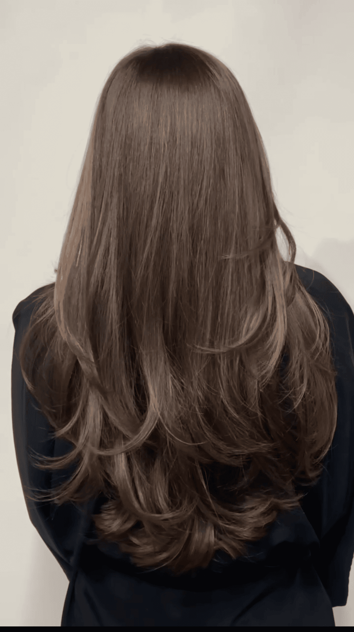 Long, silky brown hair cascading down a person's back against a light background.